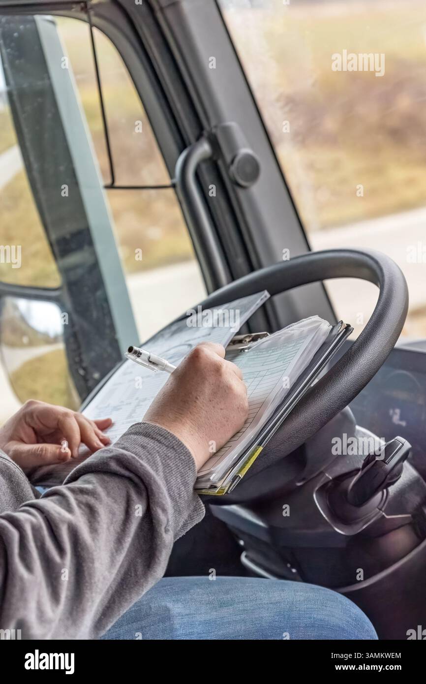 Der Fahrer überprüft die Arbeitsunterlagen im Fahrzeug. Alle potenziellen Marken werden entfernt. Vertikal. Stockfoto