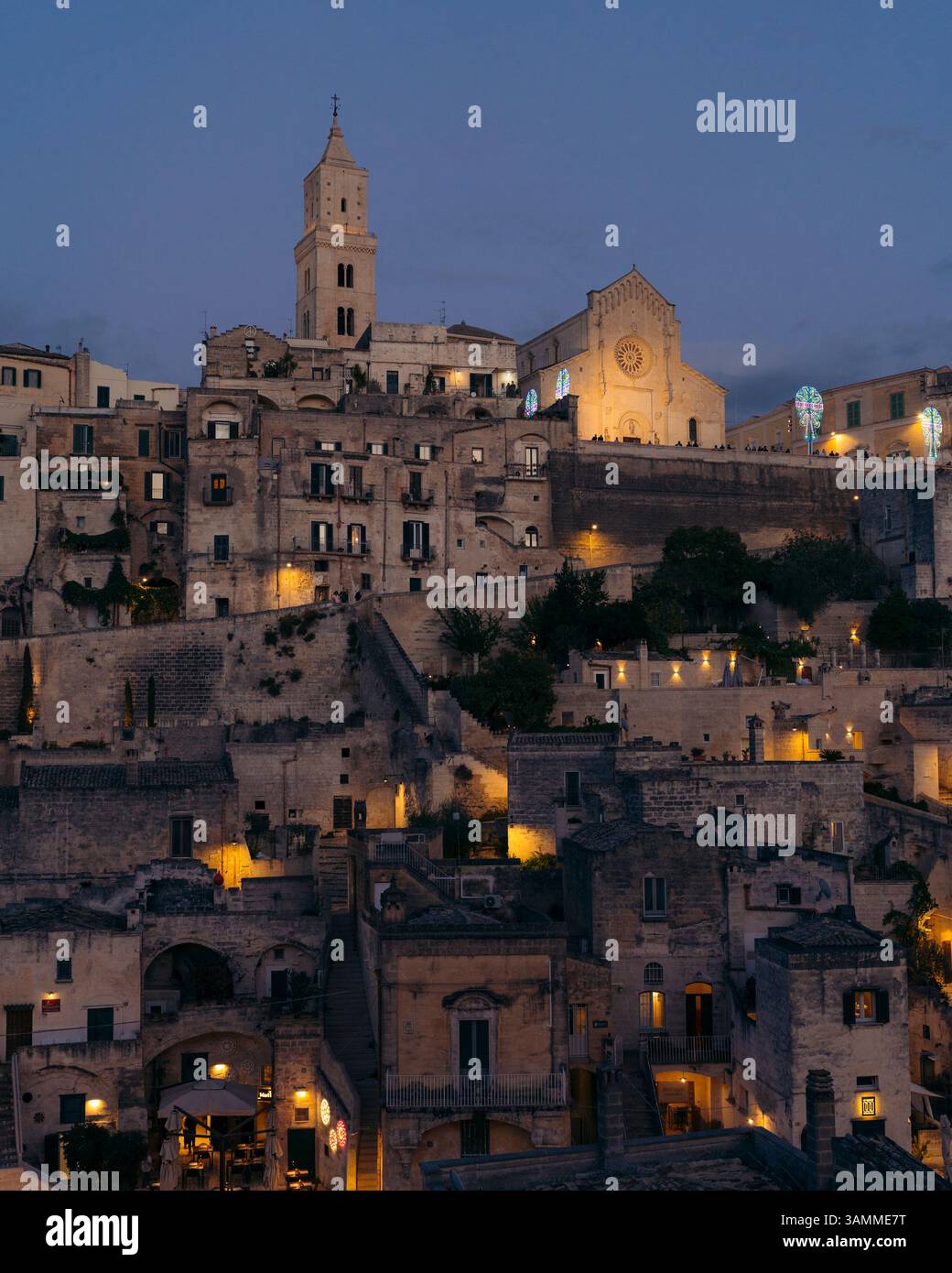 Blick aus der Vogelperspektive auf den Duomo di Matera bei Sonnenuntergang mit beleuchteten Dächern und historischer Architektur, Matera, Italien. Stockfoto