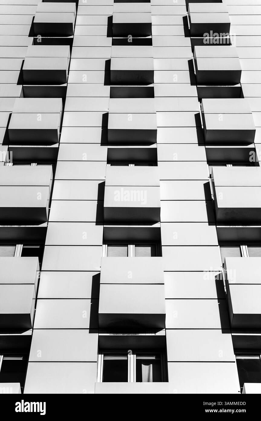 Moderne Apartmentfassade mit sich wiederholenden Balkonen und kontrastreichem Schwarz-weiß-Schattendesign für urbane Architektur Stockfoto