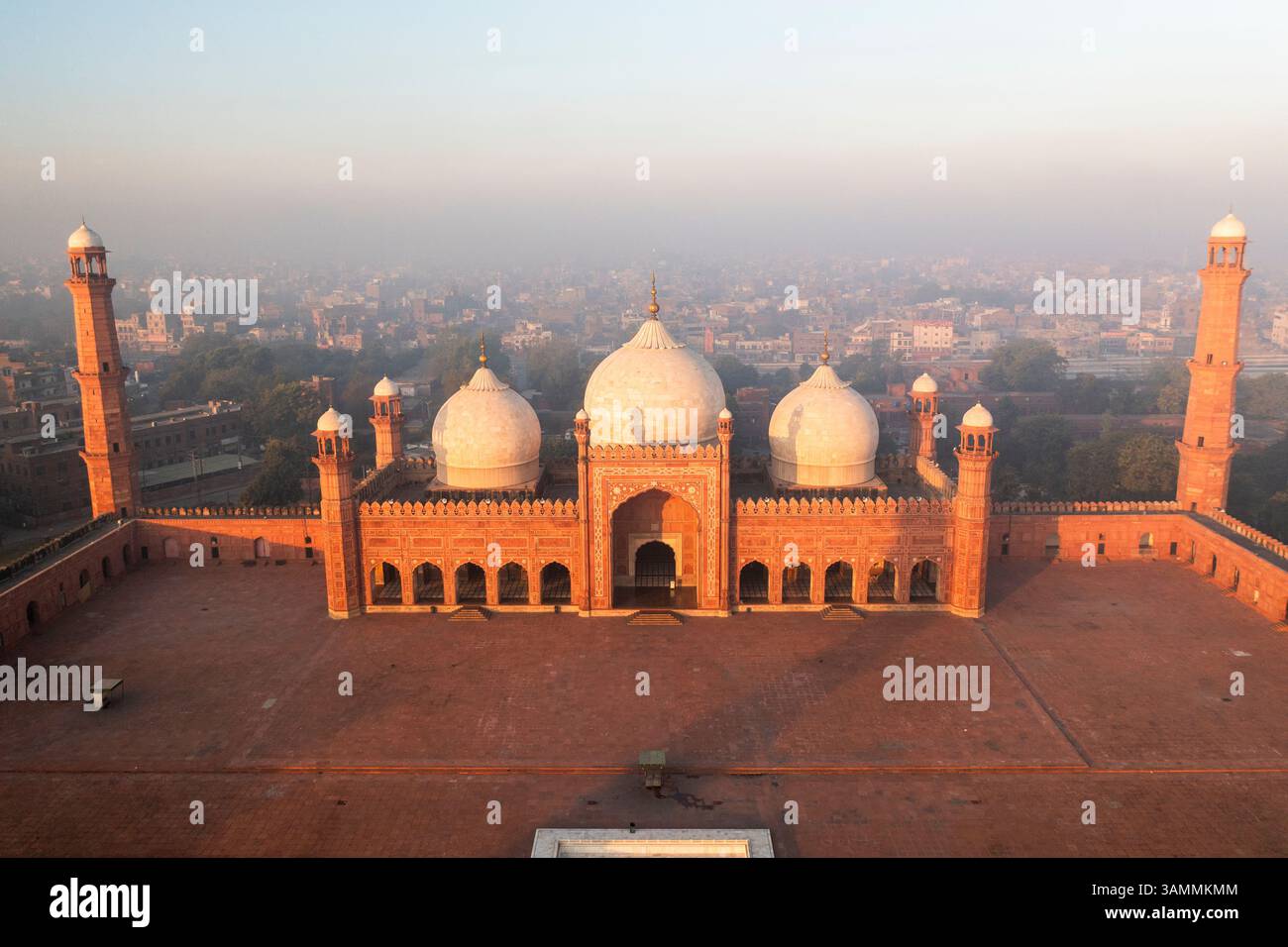Blick aus der Vogelperspektive auf die majestätische Badshahi-Moschee mit ihren berühmten Kuppeln und Minaretten, umgeben von einer lebhaften Stadtlandschaft, Lahore, Pakistan. Stockfoto