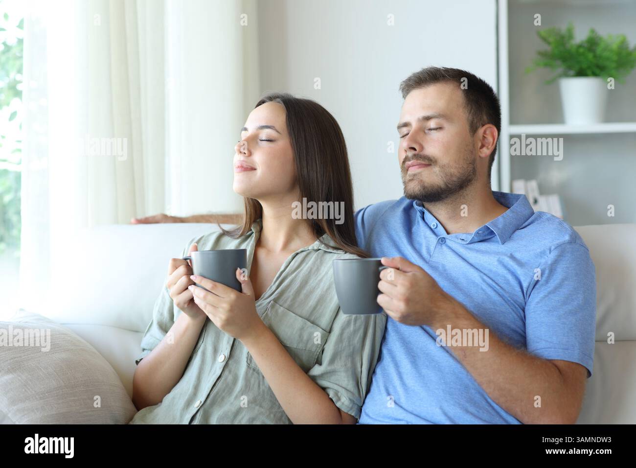 Ein Paar riecht Kaffee und sitzt zu Hause auf einer Couch Stockfoto