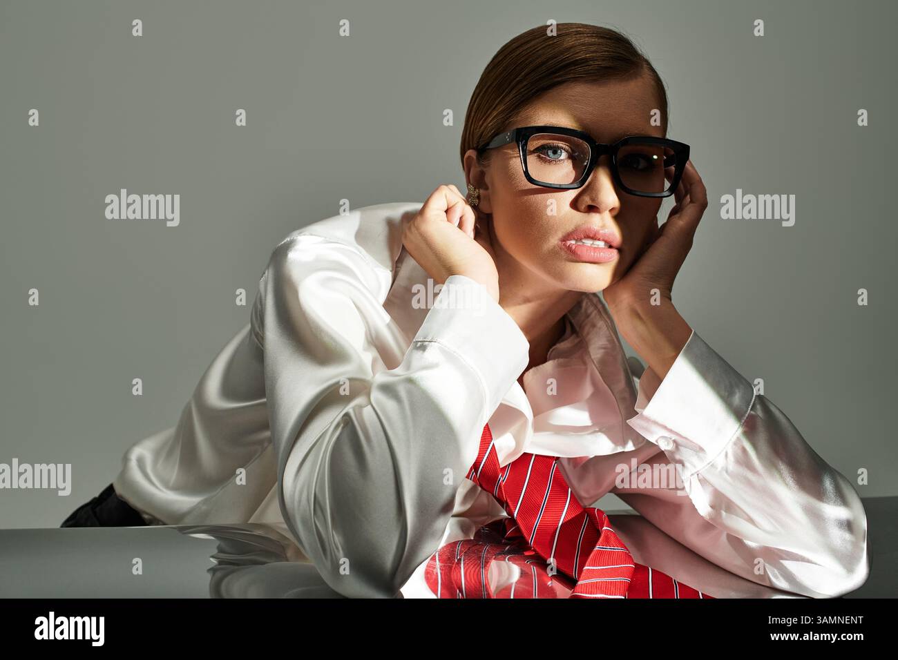 Eine junge Frau posiert selbstbewusst in einem Studio und präsentiert ihr stilvolles und elegantes Outfit. Stockfoto