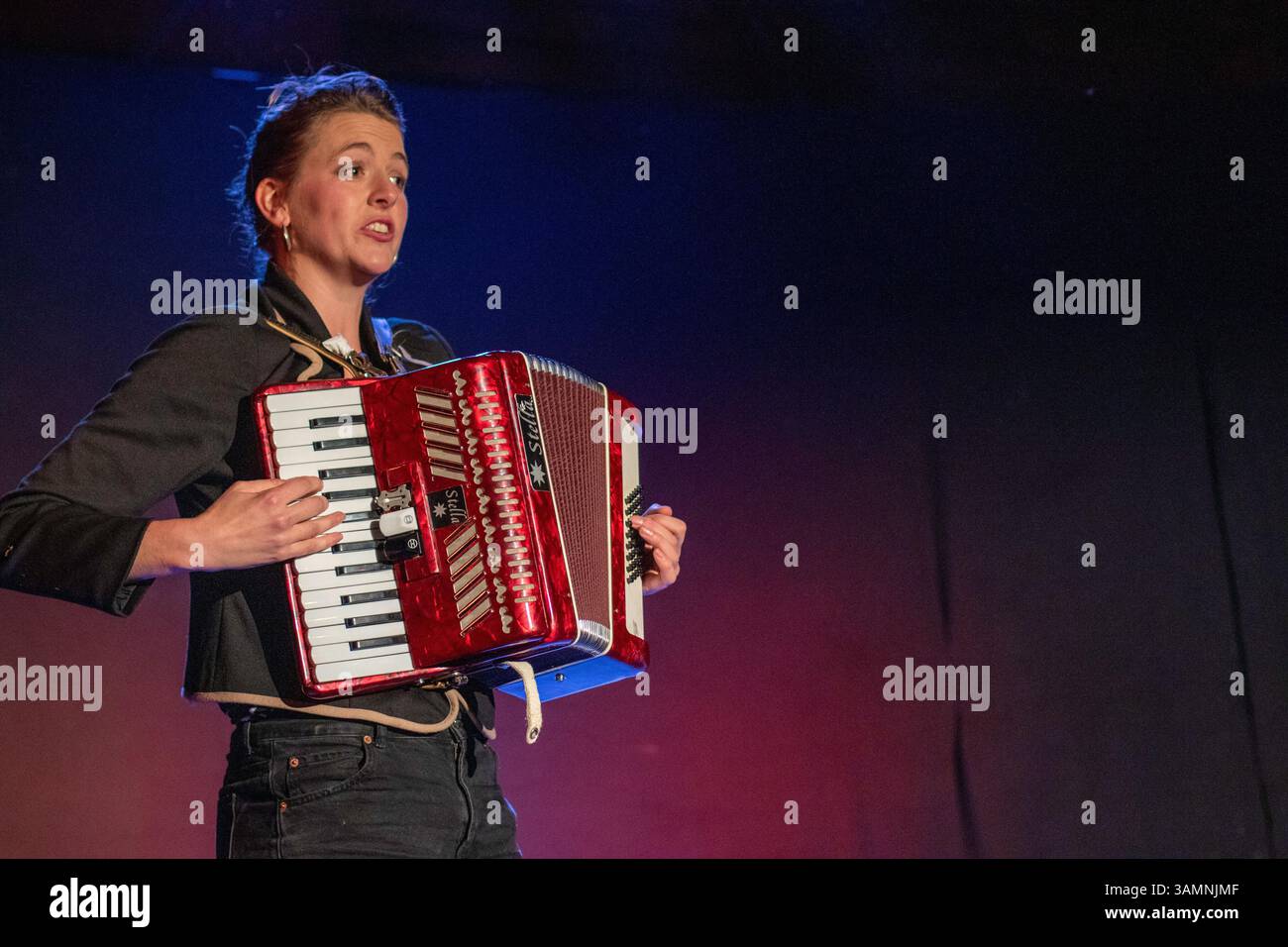 In einer Varieté-Show im Slate Barn Sweffling spielt eine junge Frau ein Stella-Klavierakkordeon und singt während ein Bühnenwechsel stattfindet. Stockfoto