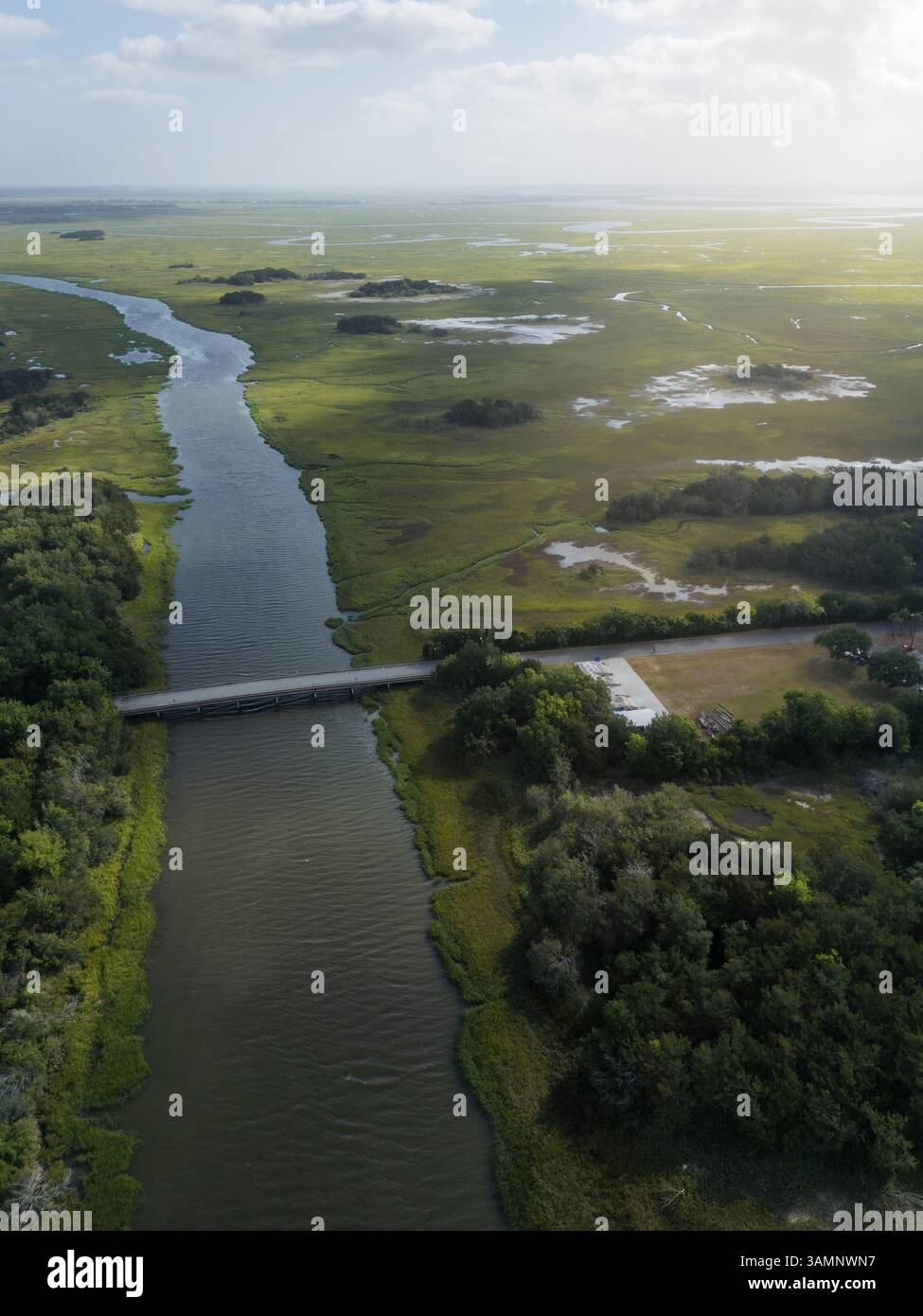 Aus der Vogelperspektive auf eine malerische Brücke über einen sich schlängelnden Fluss, umgeben von üppigen Feuchtgebieten und ruhiger Natur, Brunswick, Georgia, USA. Stockfoto