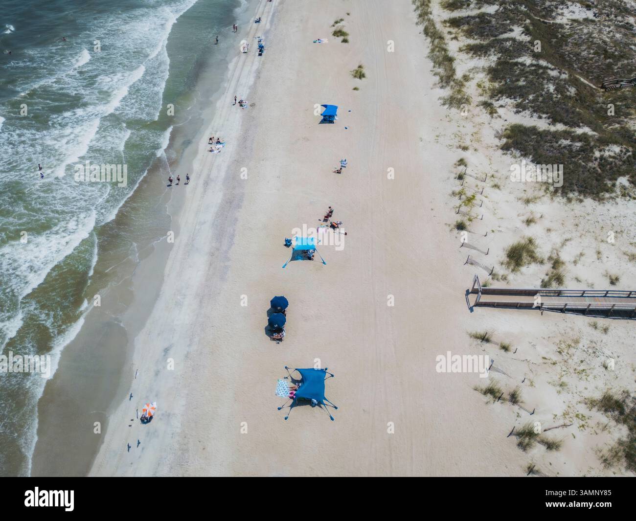 Aus der Vogelperspektive auf einen wunderschönen Strand mit Wellen und Menschen, die sich auf Sanddünen entspannen, Tybee Island, USA. Stockfoto