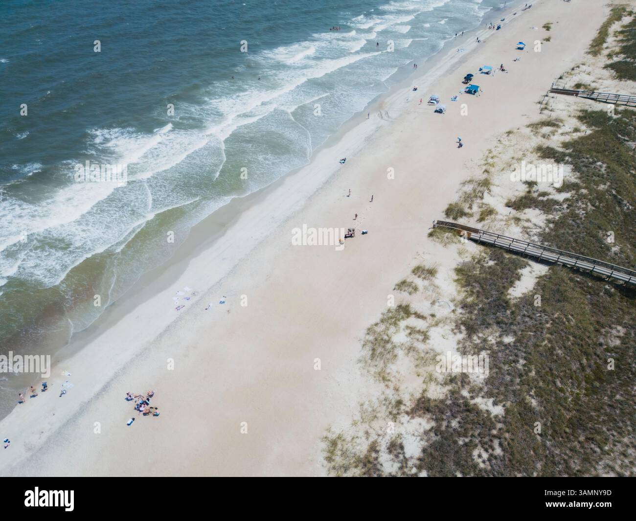 Aus der Vogelperspektive auf einen sonnigen Strand mit Wellen und Menschen in der Nähe von Sanddünen, Tybee Island, USA. Stockfoto