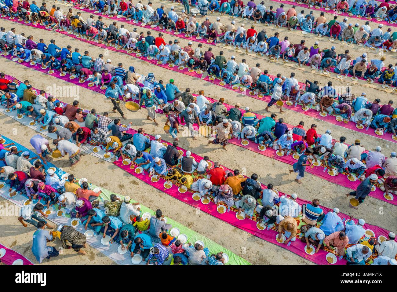 Bogura, Bangladesch - 12. Februar 2021: Aus der Vogelperspektive eines pulsierenden öffentlichen Majlis-Essens mit einer großen Menschenmenge, die in Einheit feiert, Sekherkola, Bogura, Rajshahi, Bangladesch. Stockfoto