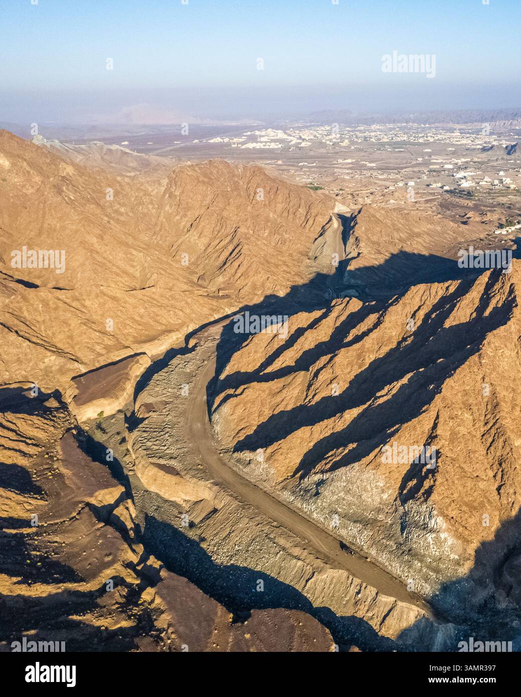 Aus der Vogelperspektive eines Canyons zwischen den felsigen und trockenen Bergen in der Wüste im Bundesstaat Ajman, Vereinigte Arabische Emirate. Stockfoto