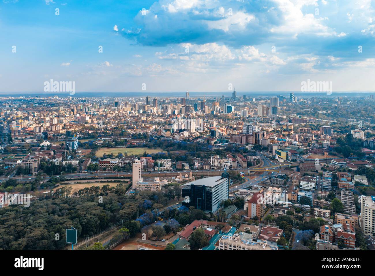 Blick aus der Vogelperspektive auf die geschäftige Skyline der Stadt mit modernen Gebäuden und belebten Straßen bei einem pulsierenden Sonnenuntergang, Parklands, Nairobi, Kenia. Stockfoto