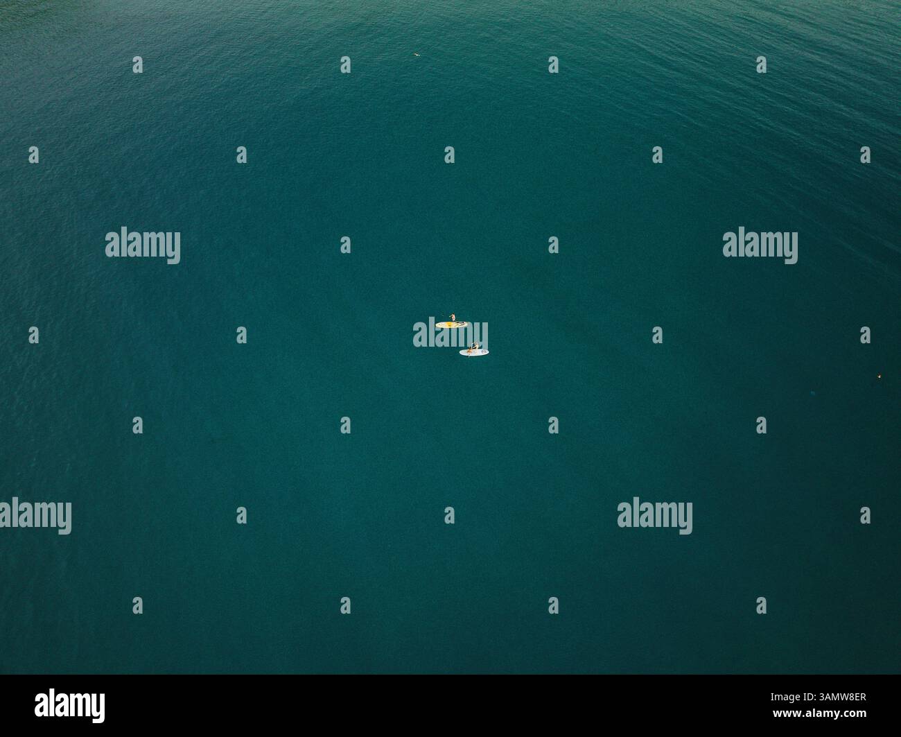 Aus der Vogelperspektive von zwei winzigen Leuten, die in Cefalù, Sizilien, Italien, mit dem Kanu ins Meer fahren. Stockfoto