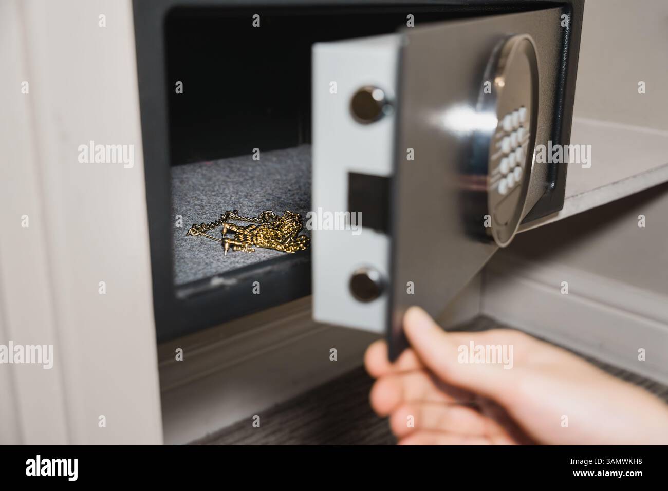 Nahaufnahme von Goldschmuck, der in einem kleinen offenen Safe aufbewahrt wird und sichere Aufbewahrung zu Hause oder im Hotel zeigt. Reisesicherheit, Schutz vor Wertsachen Stockfoto