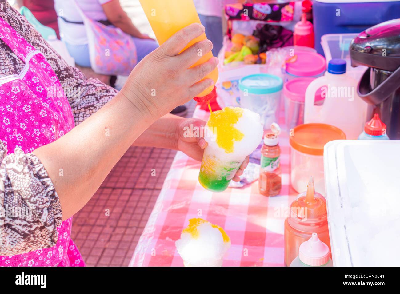Nahaufnahme der Hände einer älteren Latina, die an einem sonnigen Sommertag ein rasiertes Eis an einem Straßenstand zubereitete Stockfoto