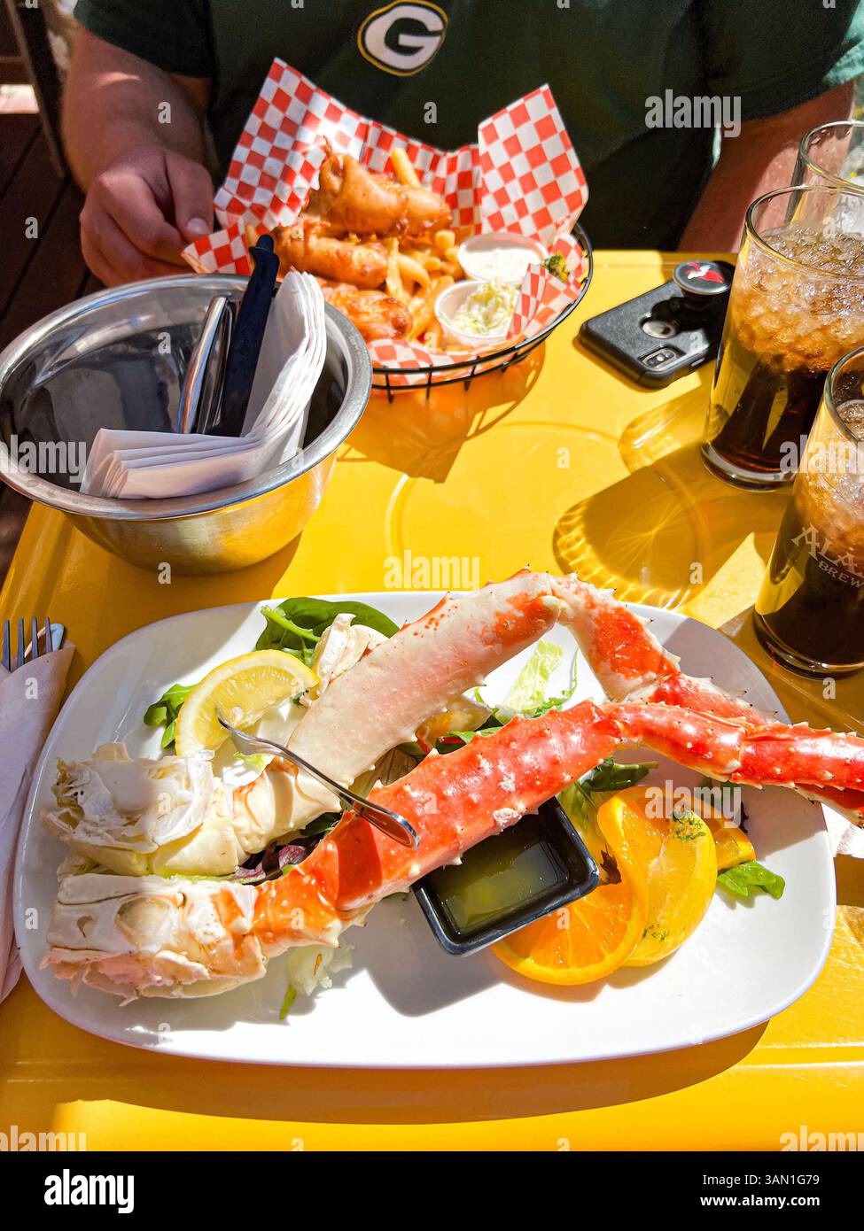 Genießen Sie Sonnenschein und Meeresfrüchte mit butterweichen Königskrabbenbeinen und knusprigen Fish & Chips – frisch und voller Geschmack. - Smartphone-aufgenommenes Stockfoto