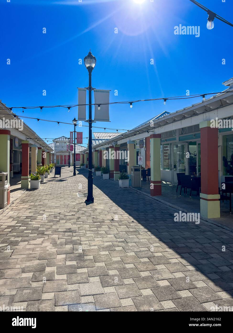 Ein ruhiger Moment im hellen und pulsierenden Einkaufsviertel unter der Mittagssonne, perfekt zum Erkunden lokaler Geschäfte und zum Genießen des Inselcharms. - Smartphone-aufgenommenes Stockfoto