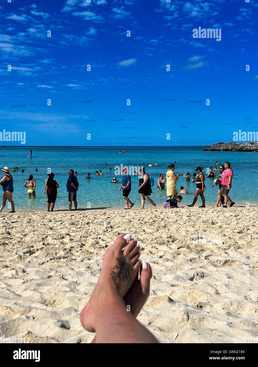 Genießen Sie die Sonne und die Aussicht an einem perfekten Strandtag, umgeben von türkisfarbenem Wasser und fröhlichen Urlaubern. - Smartphone-aufgenommenes Stockfoto