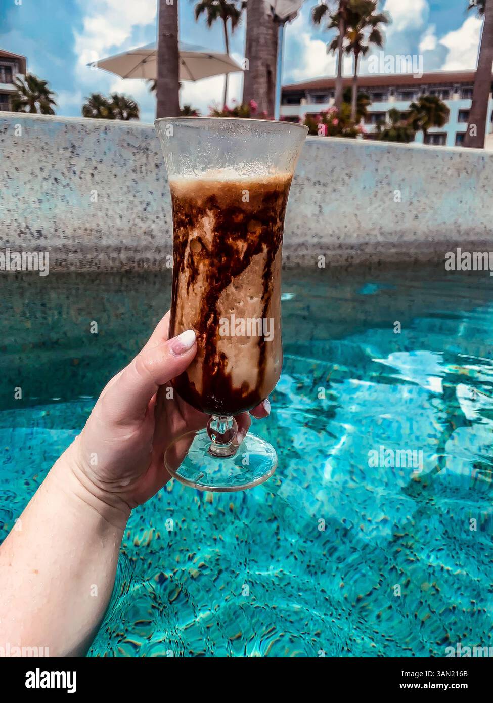Kühlen Sie sich mit einem gefrorenen Schokoladengetränk ab, während Sie die Sonne im Pool genießen. Urlaubsstimmung pur. - Smartphone-aufgenommenes Stockfoto