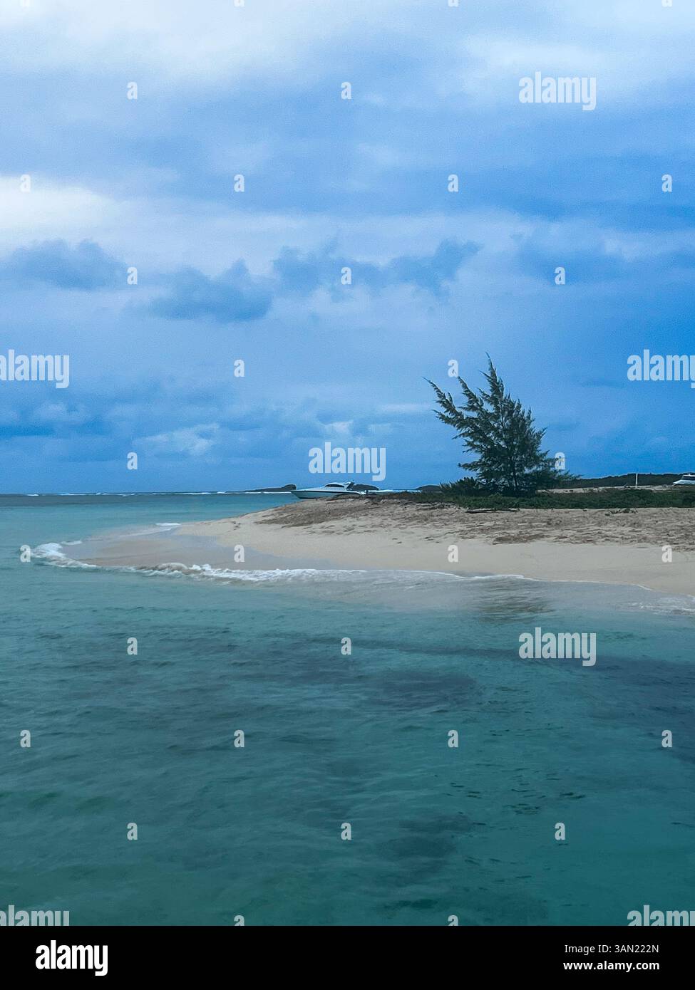 Eine friedliche, abgeschiedene Sandbar umgeben von türkisfarbenem Wasser, bietet eine ruhige Zuflucht. Der bewölkte Himmel verleiht der ruhigen Küste einen dramatischen Touch - Smartphone-aufgenommenes Stockfoto