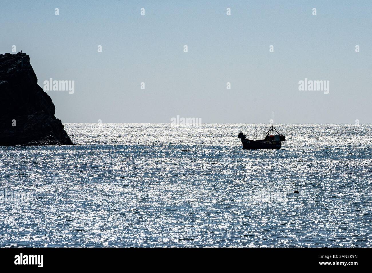 Zurück mit dem Verschluss. Ein kleines Fischerboot kehrt im Morgenlicht in Lulworth Cove, Dorset, Großbritannien, zurück Stockfoto