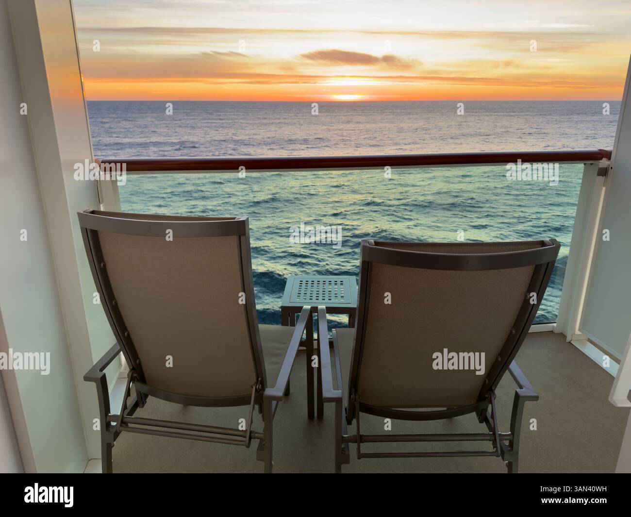 Zwei Stühle und ein Tisch auf dem Balkon der Kreuzfahrtkabine mit Blick auf das Meer, den Horizont und den Sonnenuntergang - Smartphone-aufgenommenes Stockfoto