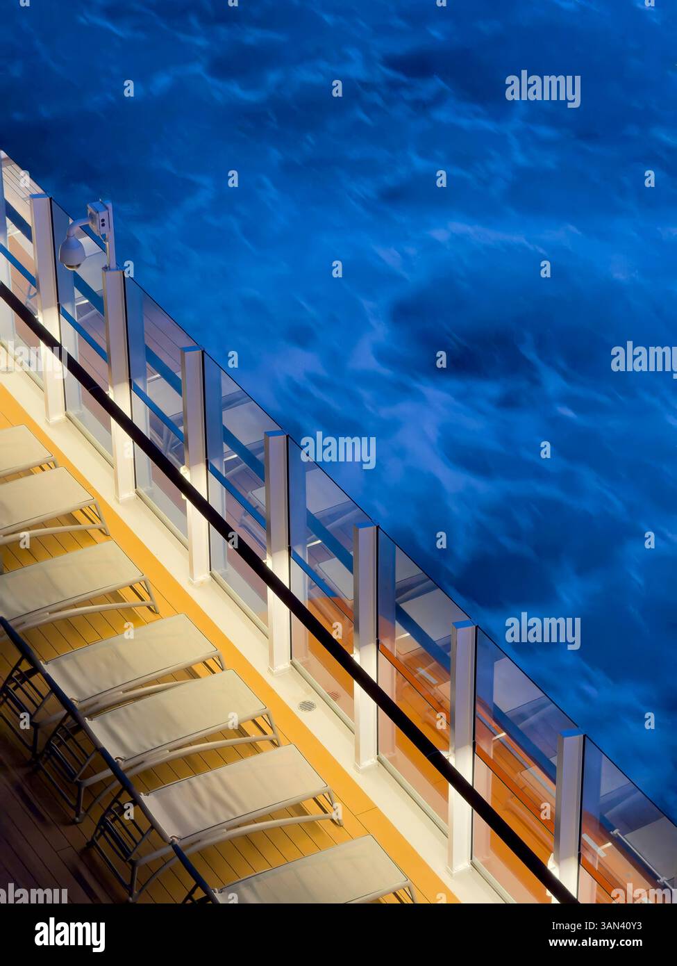 Sonnenliegen auf dem Deck des Kreuzfahrtschiffes mit Meer und Wellen, die vorbeiziehen, Sonnenuntergang - Smartphone-aufgenommenes Stockfoto