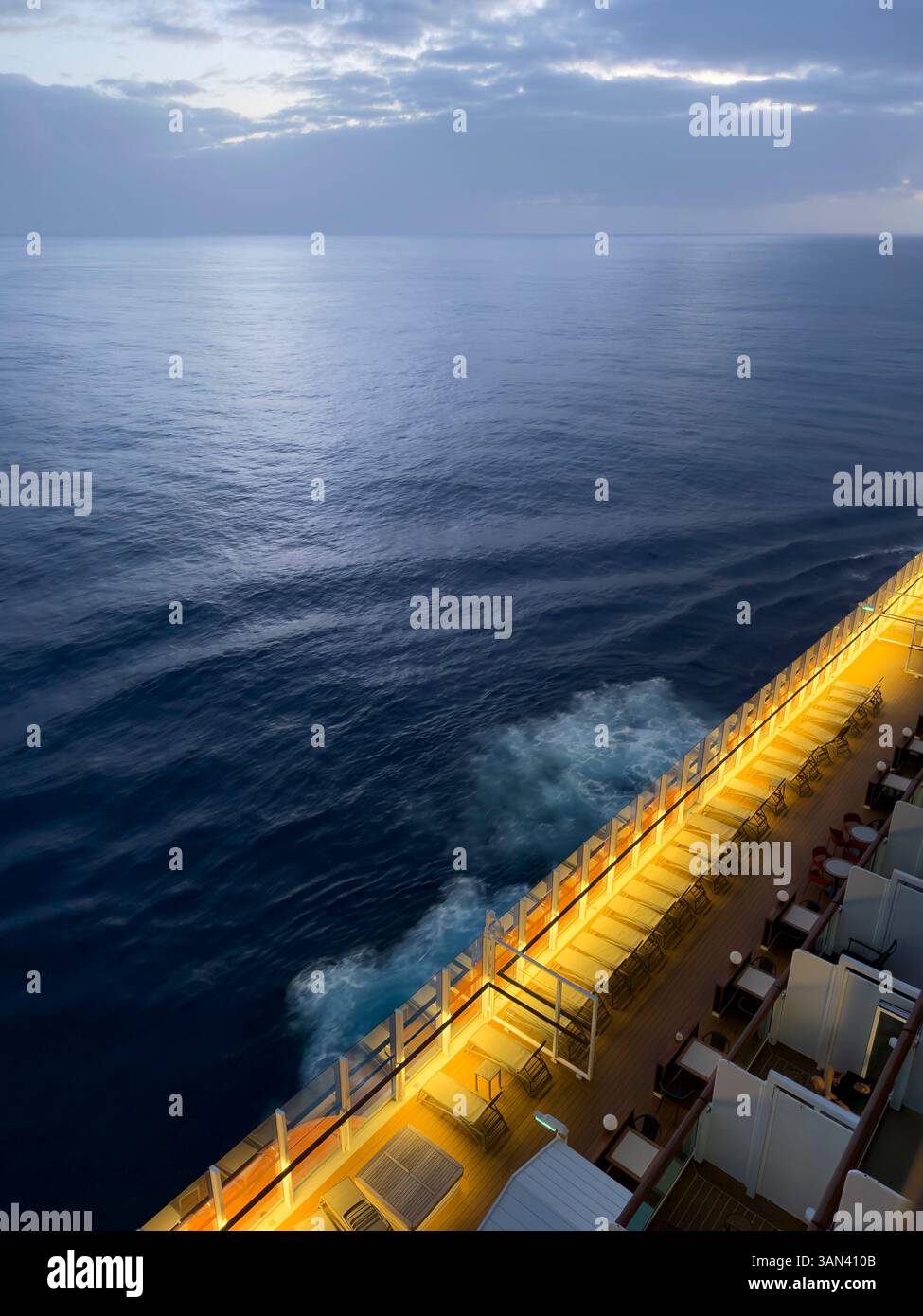 Sonnenliegen auf dem Deck des Kreuzfahrtschiffes mit Meer und Wellen, die vorbeiziehen, Sonnenuntergang - Smartphone-aufgenommenes Stockfoto