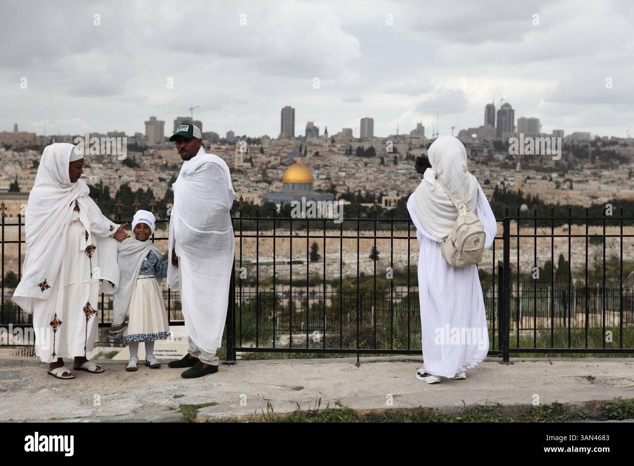 Äthiopische christliche Familie, Pilger in weiß, die mit der Felsenkuppel im Rücken fotografiert werden, bevor sie in einer Palmensonntagsprozession laufen. Stockfoto