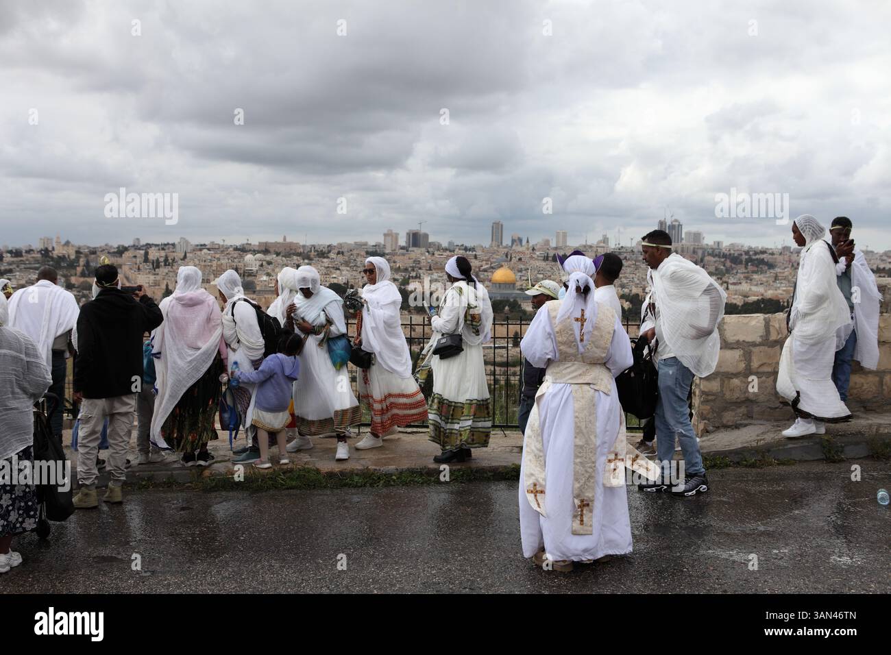 Äthiopische Christen, vor allem Frauen, die weiße Frauen tragen, mischen sich, bevor sie in eine Palmensonntagsprozession auf dem Ölberg, dem Felsendom, der hinten gesehen wird, gehen. Stockfoto