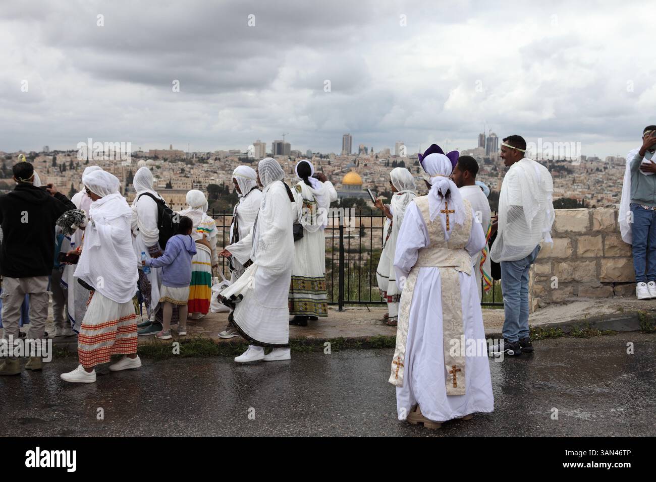 Äthiopische Christen, vor allem Frauen, die weiße Frauen tragen, mischen sich, bevor sie in eine Palmensonntagsprozession auf dem Ölberg, dem Felsendom, der hinten gesehen wird, gehen. Stockfoto