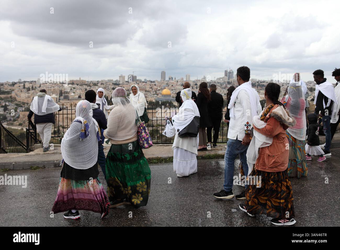 Äthiopische Christen, vor allem Frauen, die weiße Frauen tragen, mischen sich, bevor sie in eine Palmensonntagsprozession auf dem Ölberg, dem Felsendom, der hinten gesehen wird, gehen. Stockfoto