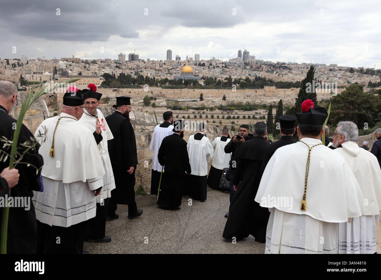 Christliche Pilger gehen vom Mt. Oliven in einer Palmensonntagsprozession mit Palmenwedel und Olivenbaumzweigen die Kuppel des Felsens gesehen. Stockfoto