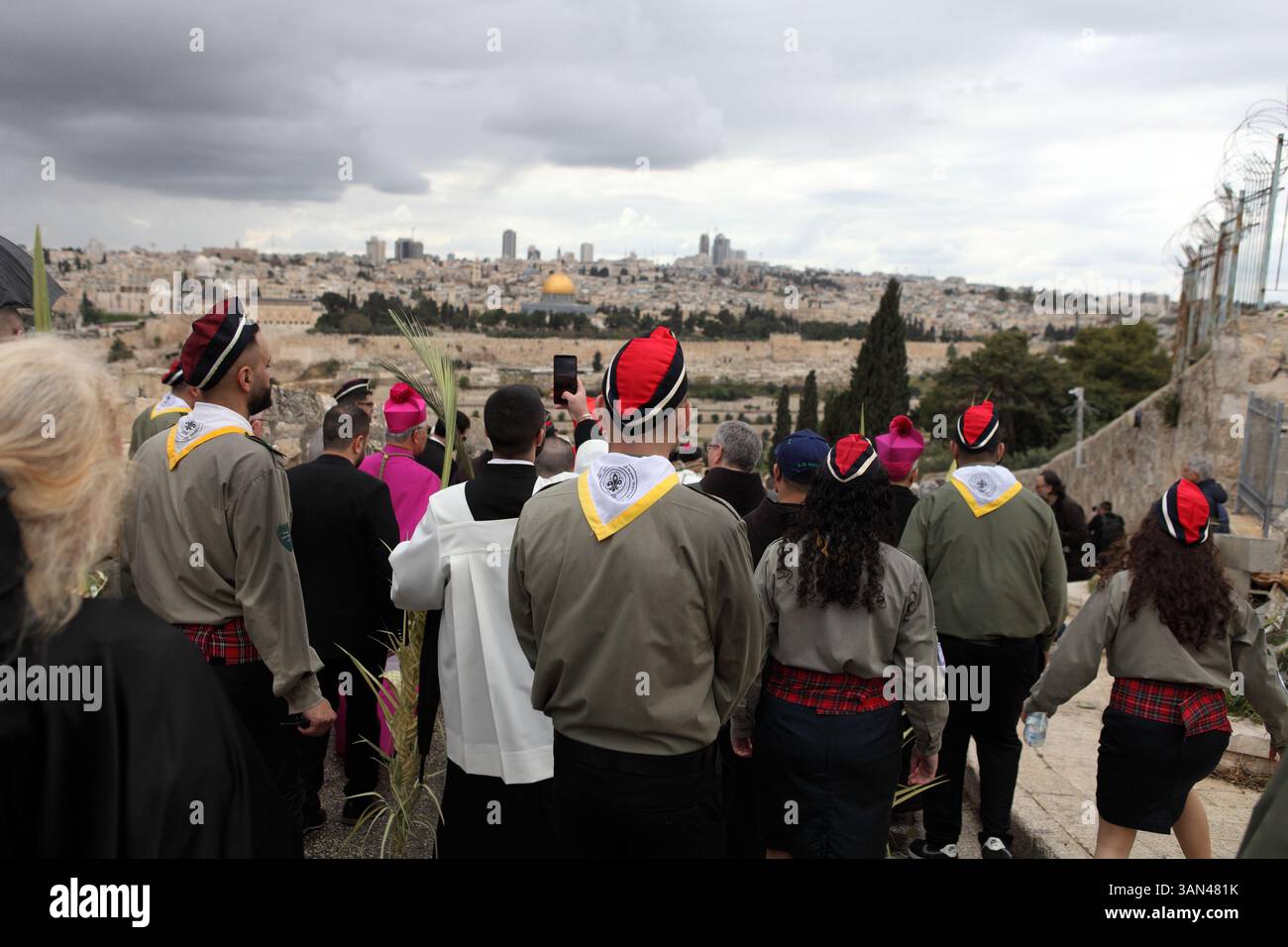 Christliche Pilger gehen vom Mt. Oliven in einer Palmensonntagsprozession mit Palmenwedel und Olivenbaumzweigen die Kuppel des Felsens gesehen. Stockfoto