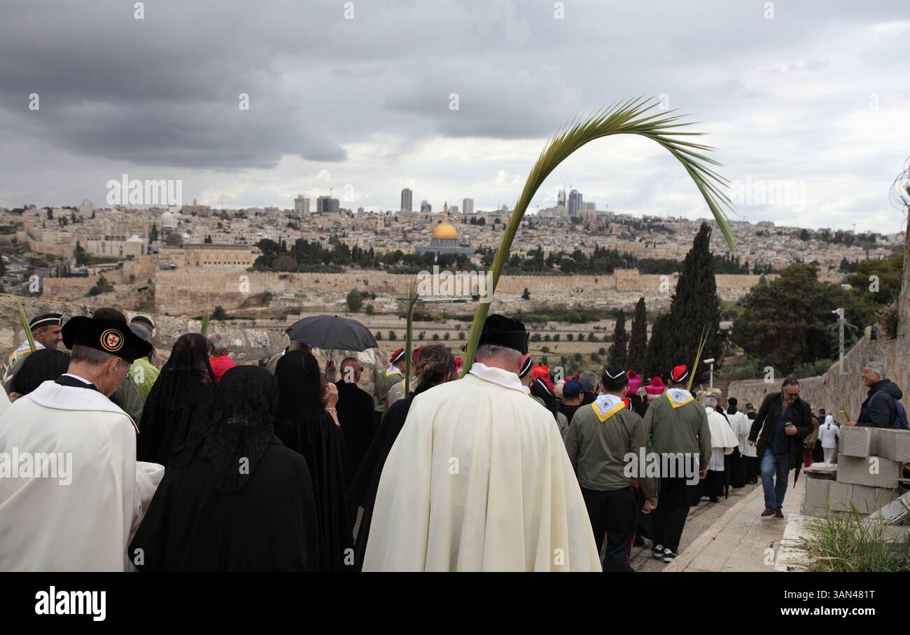 Christliche Pilger gehen vom Mt. Oliven in einer Palmensonntagsprozession mit Palmenwedel und Olivenbaumzweigen die Kuppel des Felsens gesehen. Stockfoto