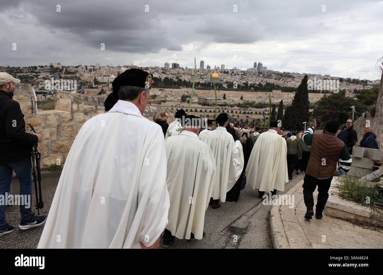 Christliche Pilger gehen vom Mt. Oliven in einer Palmensonntagsprozession mit Palmenwedel und Olivenbaumzweigen die Kuppel des Felsens gesehen. Stockfoto