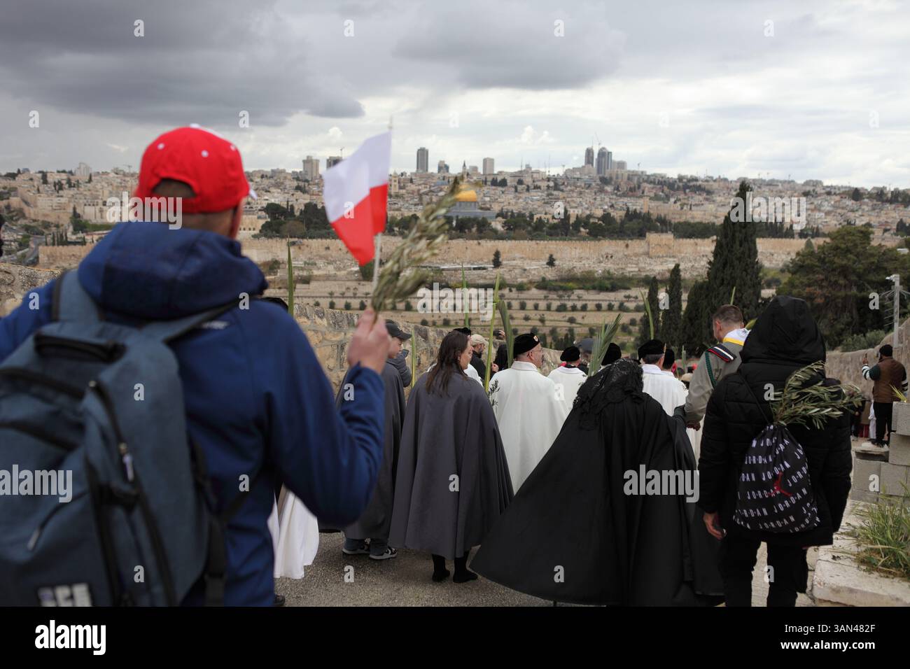 Christliche Pilger gehen vom Mt. Oliven in einer Palmensonntagsprozession mit Palmenwedel und Olivenbaumzweigen die Kuppel des Felsens gesehen. Stockfoto