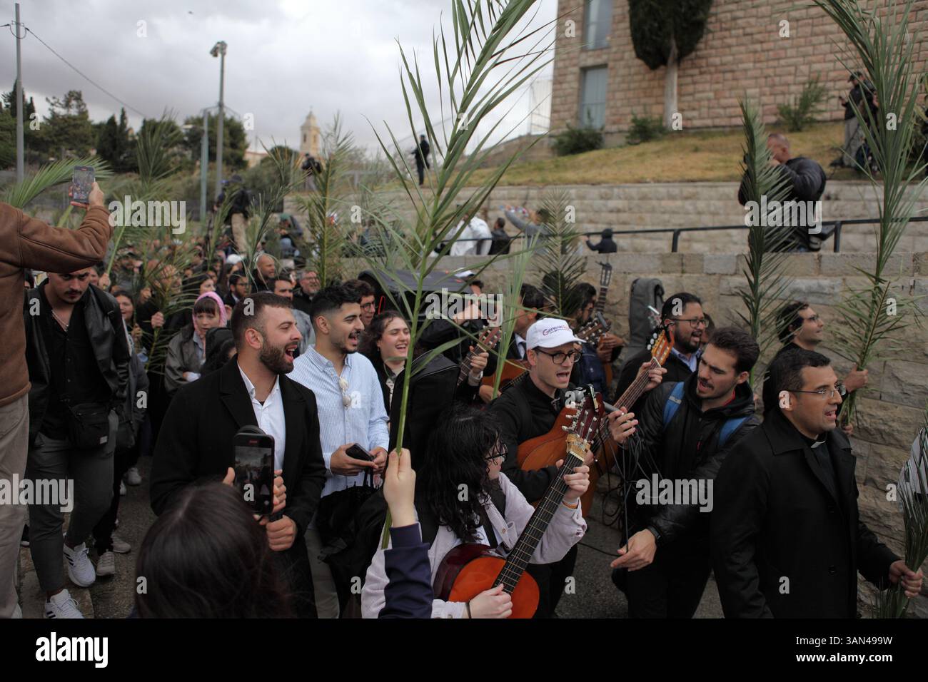 Christliche Pilger in der ganzen Welt singen und beten, während sie auf dem Mt. Oliven in einer Palmensonntagsprozession mit Palmenwedel und Olivenbaumzweigen. Stockfoto