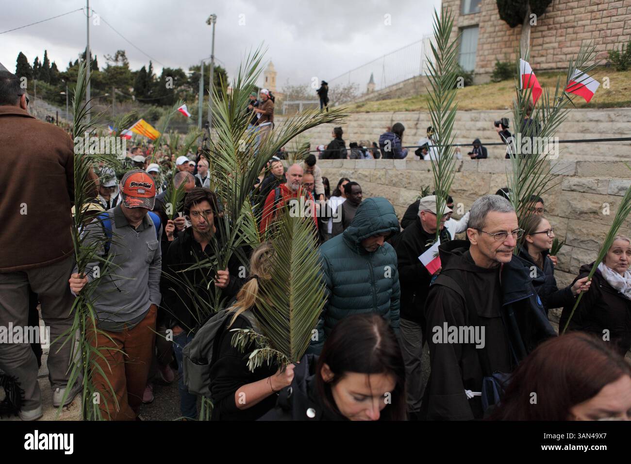 Christliche Pilger in der ganzen Welt singen und beten, während sie auf dem Mt. Oliven in einer Palmensonntagsprozession mit Palmenwedel und Olivenbaumzweigen. Stockfoto