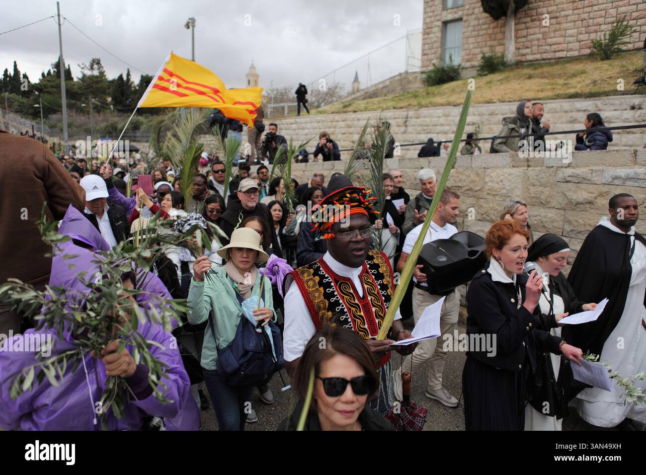 Christliche Pilger in der ganzen Welt singen und beten, während sie auf dem Mt. Oliven in einer Palmensonntagsprozession mit Palmenwedel und Olivenbaumzweigen. Stockfoto