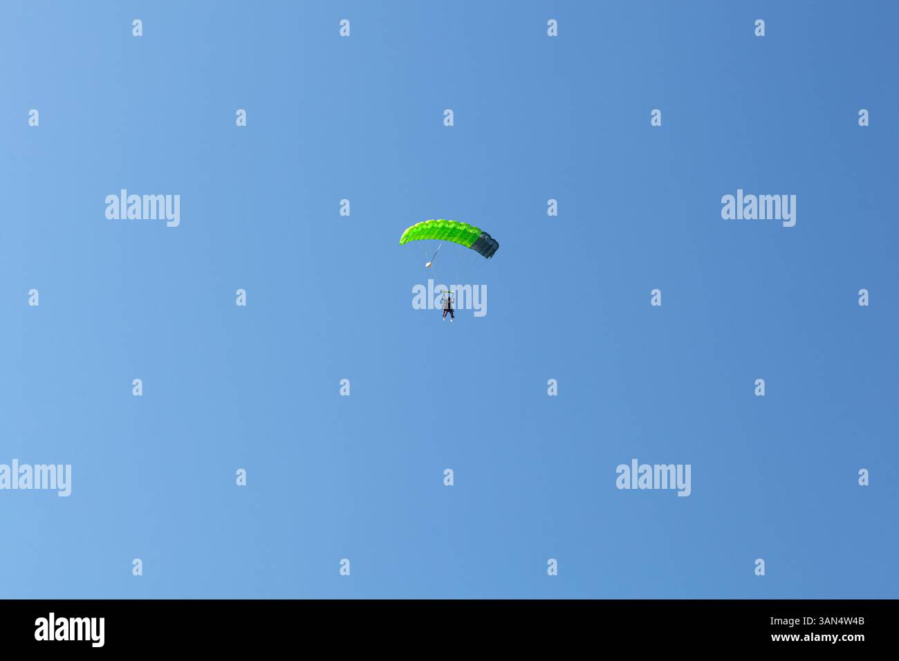 Bovec, Slowenien - 17. Juli 2025: Ein Paraglider mit grünem Fallschirm steigt mit blauem Himmel im Hintergrund nach Kanin, Slowenien, ab. Stockfoto