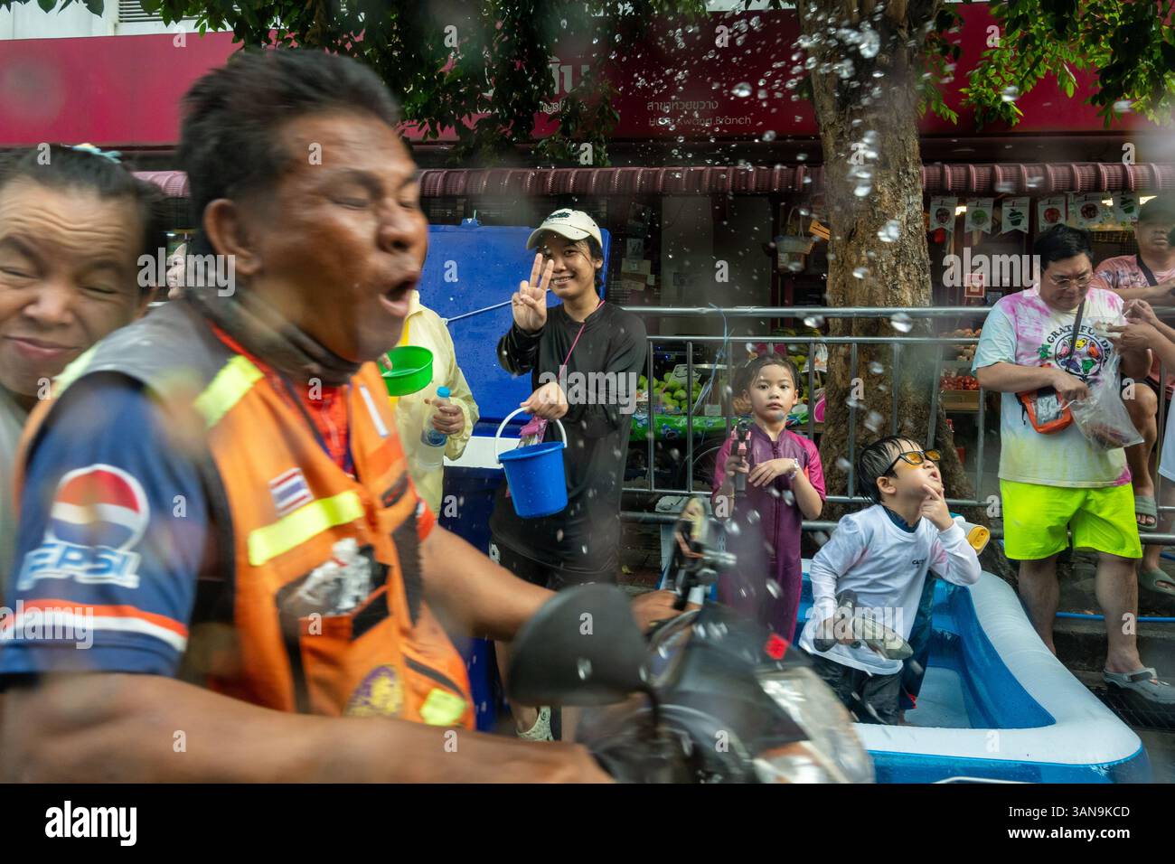 Bangkok, Thailand. April 2025. Ein Mann auf einem Motorrad erhält während des Songkran Festivals auf dem Huai Khwang Markt Wasserspritzer. Songkran, Thailands traditionelles Neujahrsfest, das ab April 13-15 stattfindet, ist eine der lebhaftesten und freudigsten Feierlichkeiten des Landes. Die Stadt ist vor allem für ihre massiven Wasserkämpfe auf den Straßen bekannt, die das Abwaschen von Unglück und Unglück symbolisieren und einen Neuanfang für das kommende Jahr darstellen. Quelle: SOPA Images Limited/Alamy Live News Stockfoto