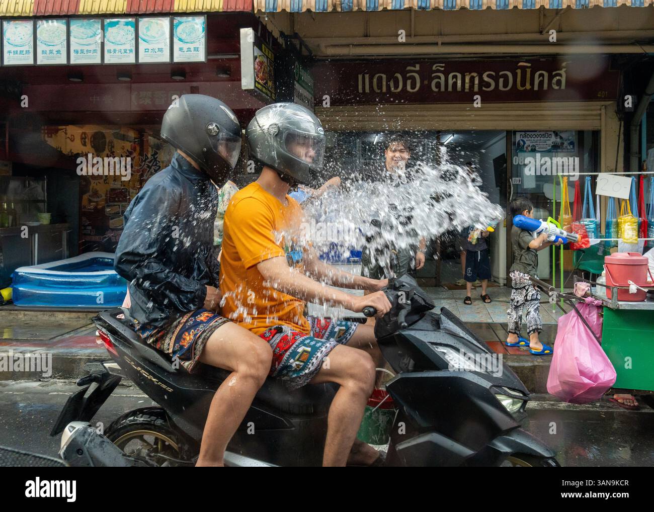 Bangkok, Thailand. April 2025. Eine Nahaufnahme von Menschen auf einem Motorrad, die während des Songkran Festivals auf dem Huai Khwang Markt mit Wasser bespritzt wurden. Songkran, Thailands traditionelles Neujahrsfest, das ab April 13-15 stattfindet, ist eine der lebhaftesten und freudigsten Feierlichkeiten des Landes. Die Stadt ist vor allem für ihre massiven Wasserkämpfe auf den Straßen bekannt, die das Abwaschen von Unglück und Unglück symbolisieren und einen Neuanfang für das kommende Jahr darstellen. Quelle: SOPA Images Limited/Alamy Live News Stockfoto