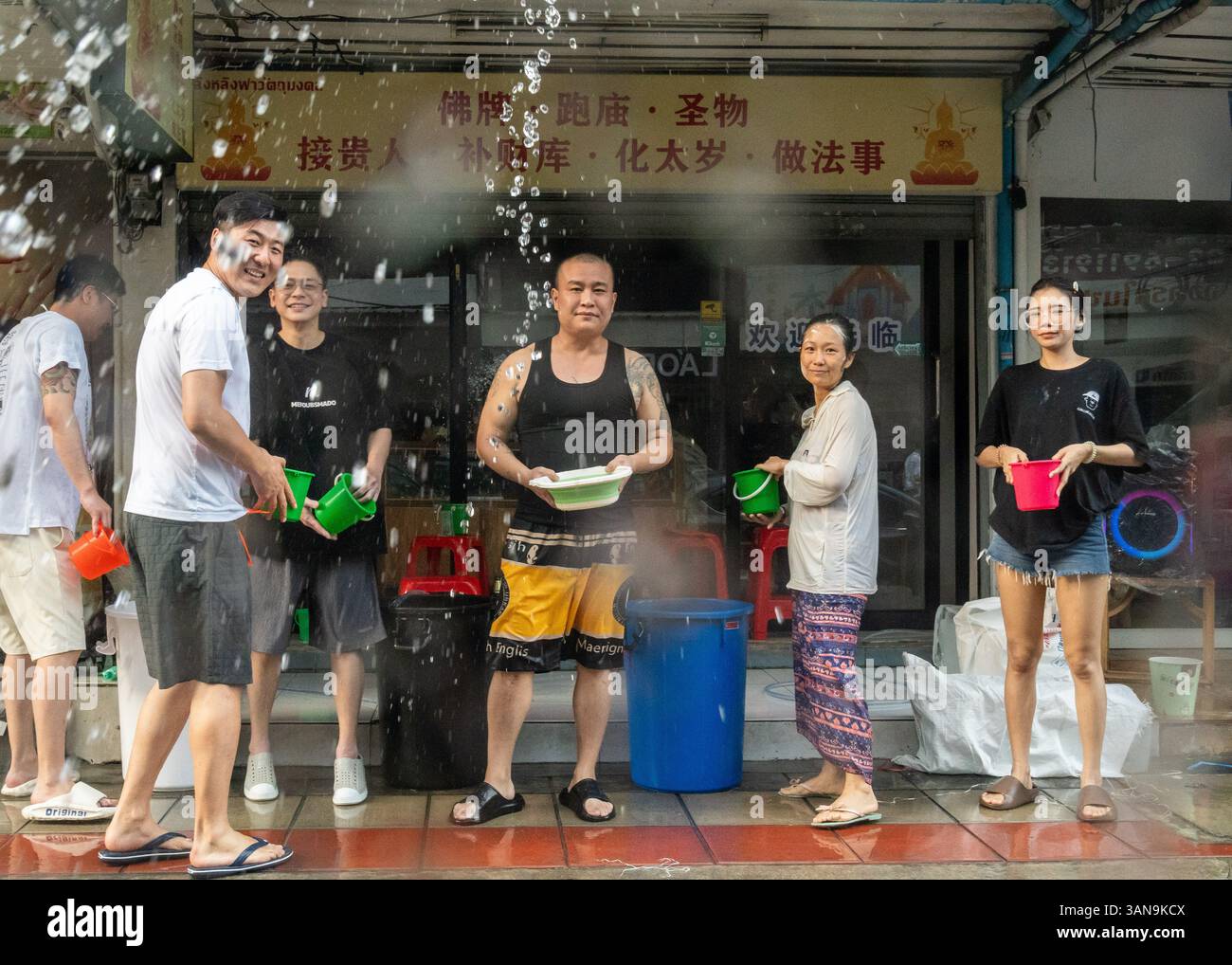 Bangkok, Thailand. April 2025. Eine chinesische Familie spielt mit Wasser vor ihrem Laden während des Songkran Festivals auf dem Huai Khwang Market. Songkran, Thailands traditionelles Neujahrsfest, das ab April 13-15 stattfindet, ist eine der lebhaftesten und freudigsten Feierlichkeiten des Landes. Die Stadt ist vor allem für ihre massiven Wasserkämpfe auf den Straßen bekannt, die das Abwaschen von Unglück und Unglück symbolisieren und einen Neuanfang für das kommende Jahr darstellen. Quelle: SOPA Images Limited/Alamy Live News Stockfoto