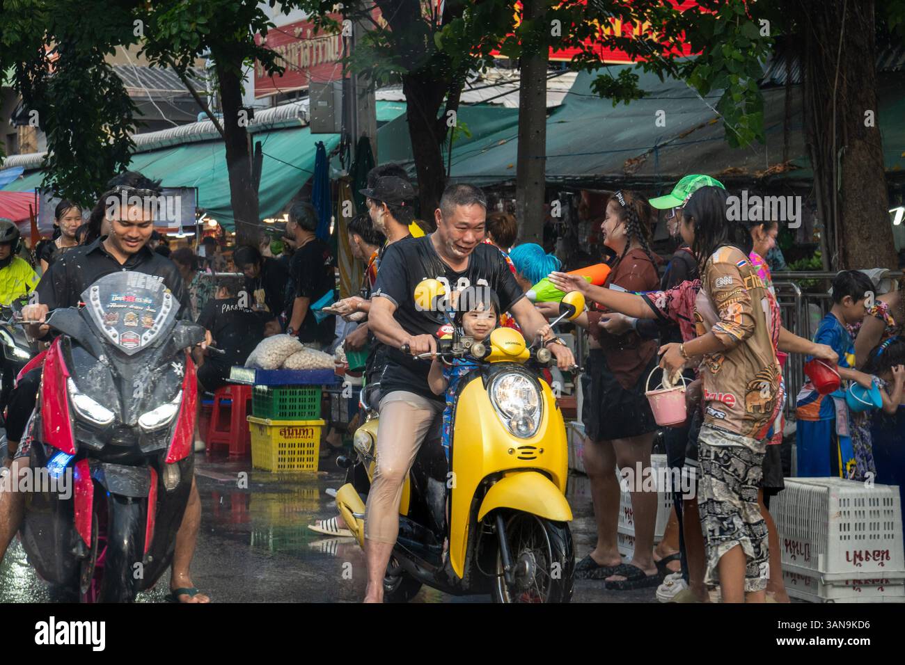 Bangkok, Thailand. April 2025. Ein Blick auf einen Vater und eine Tochter auf einem Motorrad, das während des Songkran Festivals auf dem Huai Khwang Markt Wasser empfängt. Songkran, Thailands traditionelles Neujahrsfest, das ab April 13-15 stattfindet, ist eine der lebhaftesten und freudigsten Feierlichkeiten des Landes. Die Stadt ist vor allem für ihre massiven Wasserkämpfe auf den Straßen bekannt, die das Abwaschen von Unglück und Unglück symbolisieren und einen Neuanfang für das kommende Jahr darstellen. Quelle: SOPA Images Limited/Alamy Live News Stockfoto