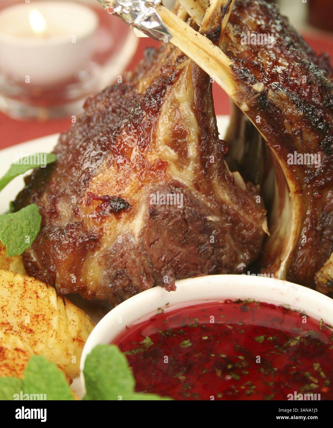Gebratenes Lammregal mit roter Johannisbeere und Minzsauce und Kartoffeln mit Paprika Stockfoto