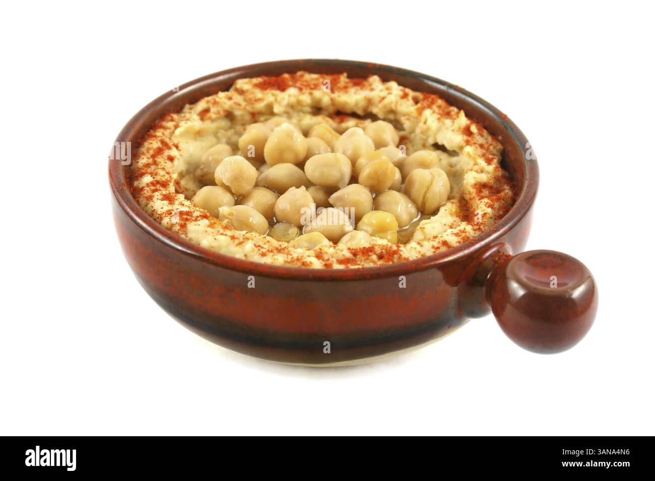 Schüssel aus Steingut mit köstlichem Hommus und Kichererbsen, bereit zum Tauchen Stockfoto