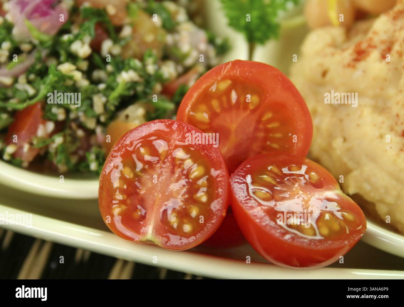 Tabouleh mit Hommus und Zitronenkichererbsen mit frischen Kirschtomatenhälften Stockfoto