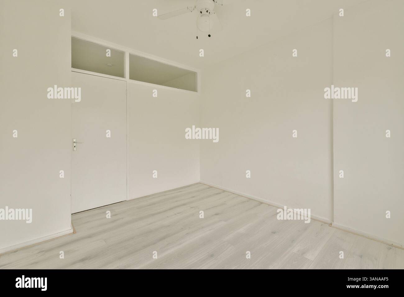 Ein heller, leerer Raum mit weißen Wänden und hellem Holzboden schafft eine ruhige und geräumige Atmosphäre, ideal für verschiedene Zwecke. Stockfoto
