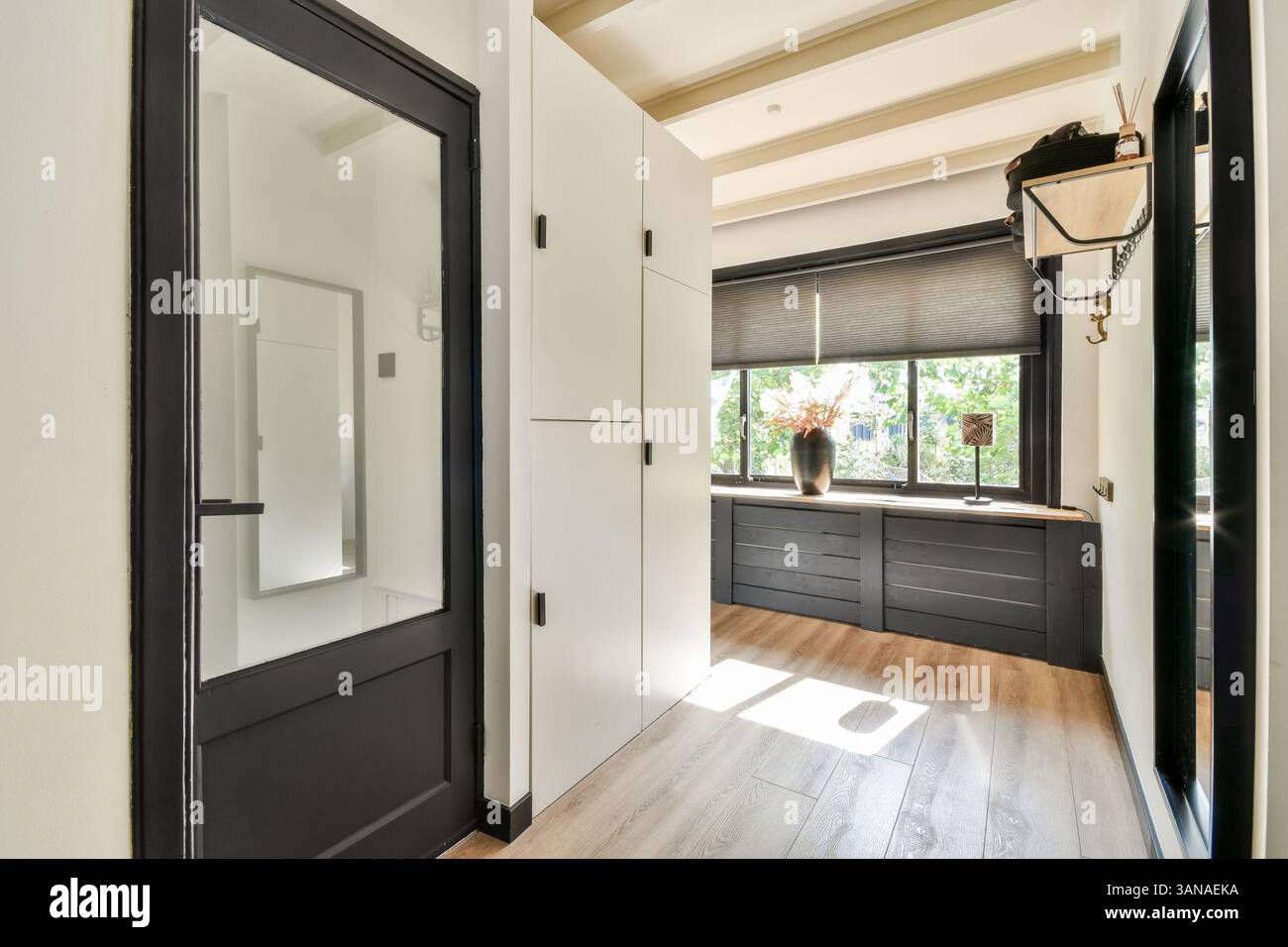 Ein eleganter Eingangsbereich mit schlanken Linien, natürlichem Licht und minimalistischer Einrichtung, die Funktionalität und ästhetischem Charme in einem modernen Zuhause vereint. Stockfoto