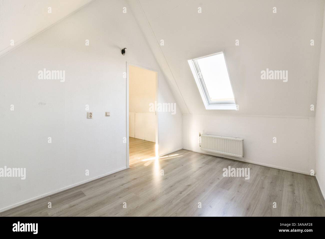 Ein geräumiges, modernes Interieur mit kantigem Design und viel natürlichem Licht durch ein Oberlicht. Die Einfachheit wird durch neutrale Töne und klare Linien verstärkt. Stockfoto