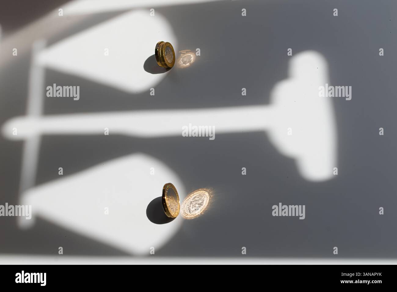 Silhouette von Waagen mit einer Pfund-Münze auf der einen und drei auf der anderen Seite, die Wert, Ungleichgewicht, Ungleichheit oder finanzielle Gerechtigkeit symbolisieren Stockfoto