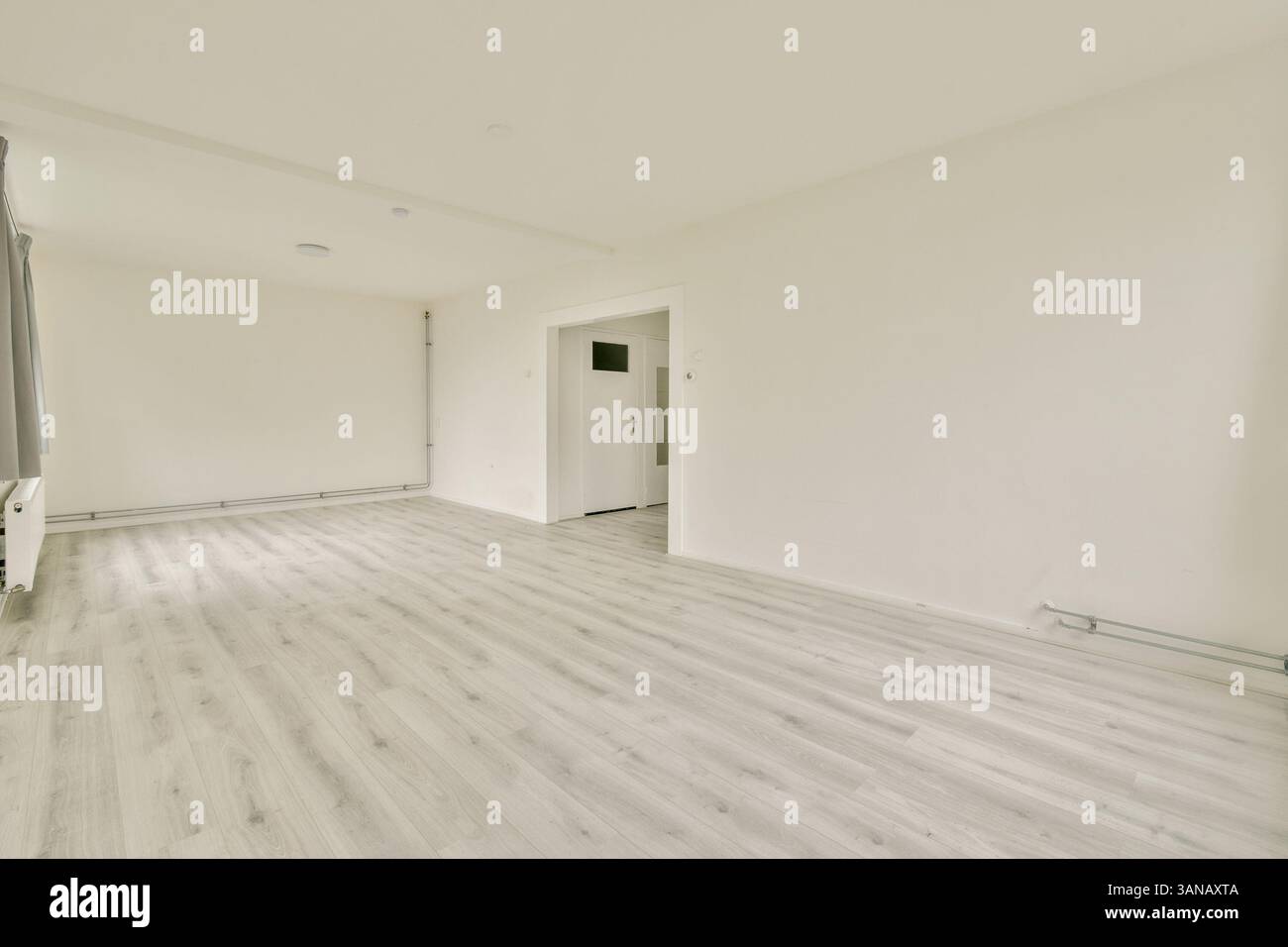 Ein geräumiges, minimalistisches Zimmer mit hellem Boden und neutralen Wänden, das eine helle und luftige Atmosphäre für verschiedene Zwecke schafft. Stockfoto